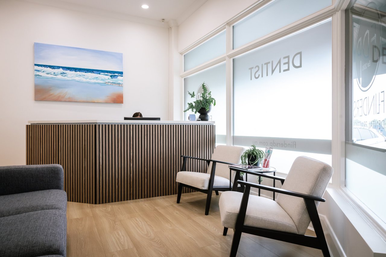 The waiting room and front desk at Flinders Dental Practice, with a beach painting on the wall and daylight through the front windows