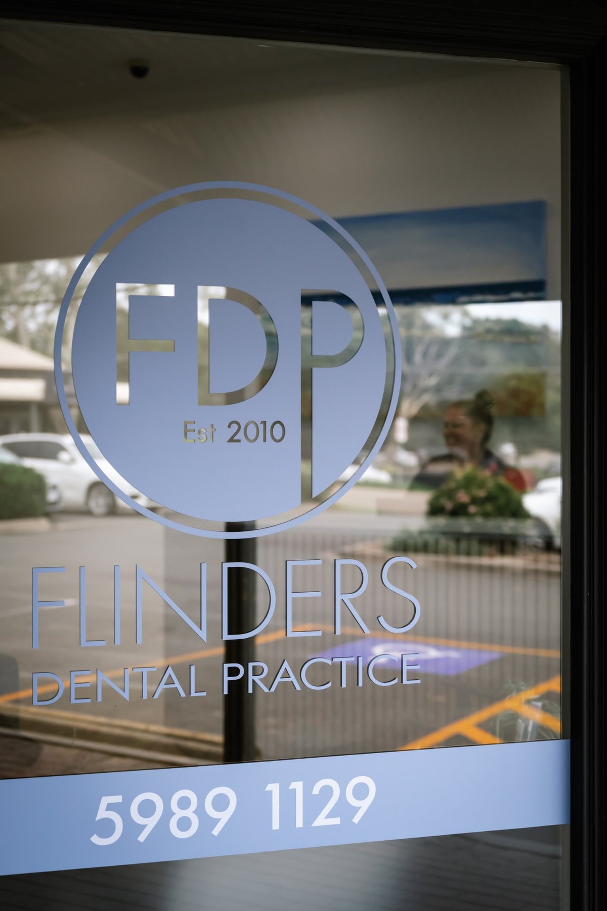 The glass front door of Flinders Dental Practice, with the FDP logo and 'Est 2010' on the glass